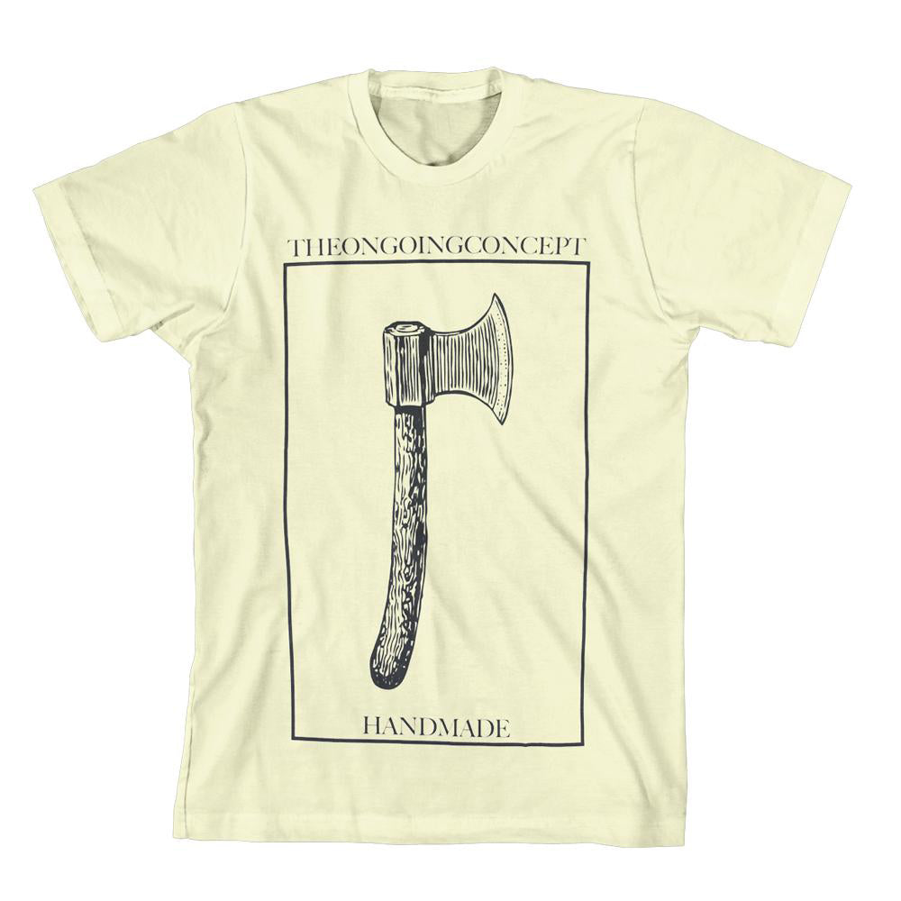 cream colored tee against white background. there is a large vertical rectangle that is a thin line outline. inside this is a drawing of an axe in black. on top of the rectangle reads "the ongoing concept" in black text. inside the bottom of the rectangle in black text reads "handmade".